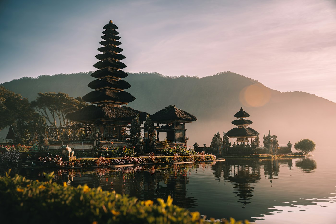 A tiered Balinese temple reflected in a still lake at sunrise