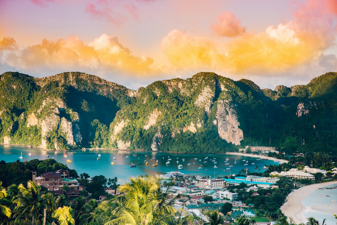 Limestone cliffs and longtail boats around a turquoise bay in southern Thailand